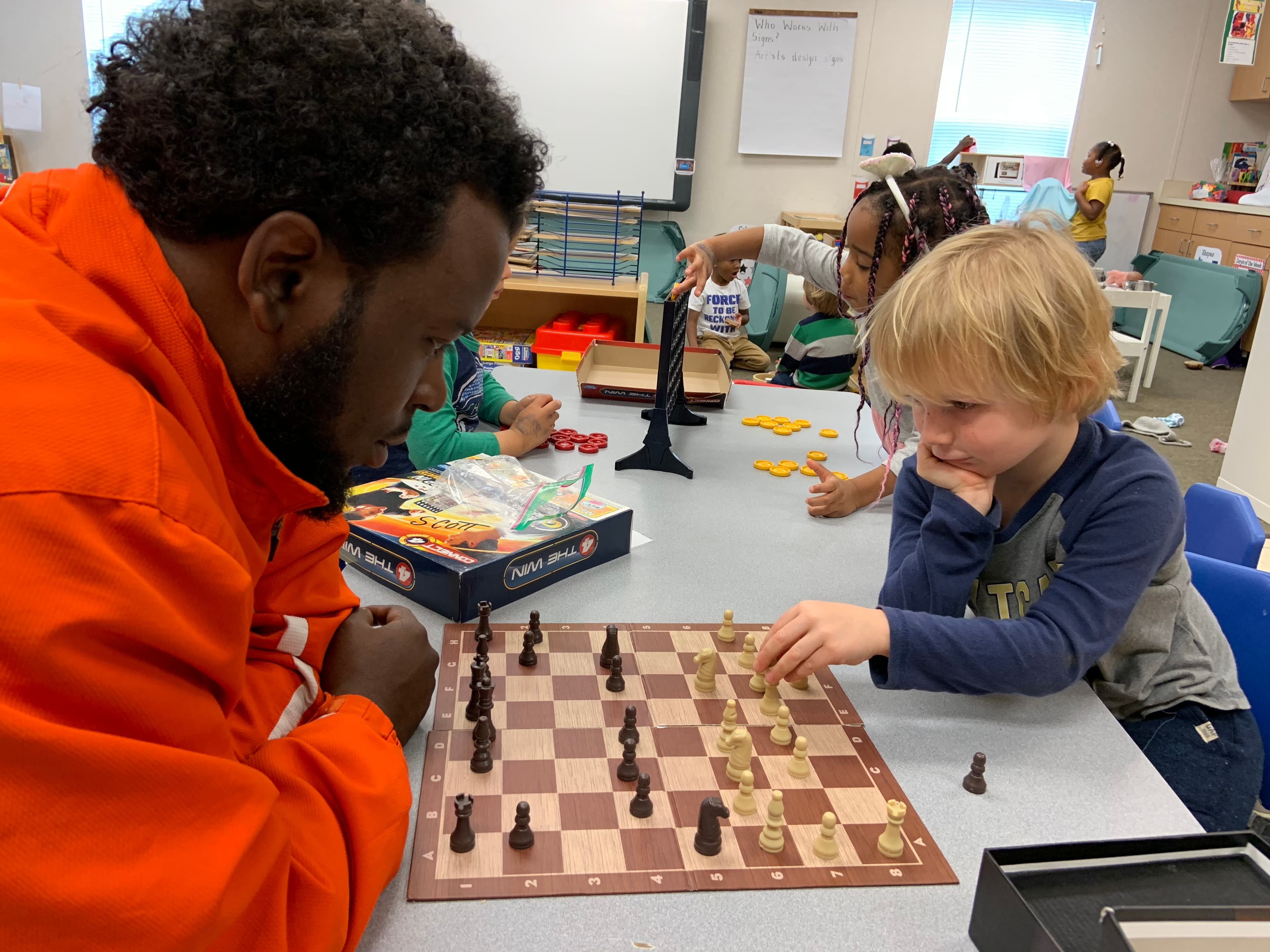 Coach Rodolfo working with a young student over a chessboard